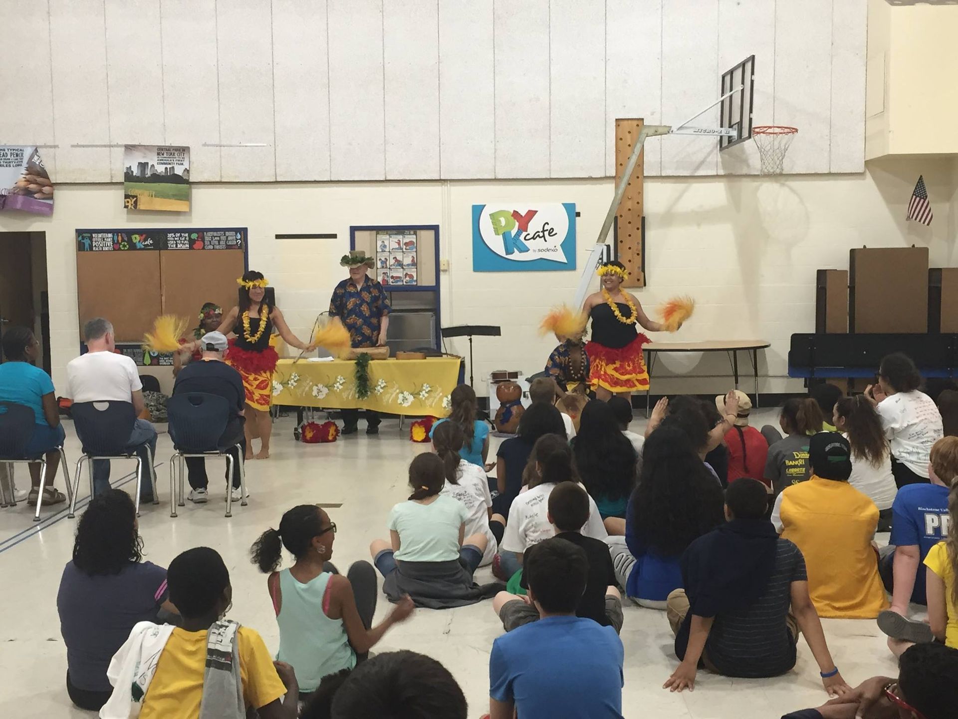 A group of people are sitting in a gym watching a performance.