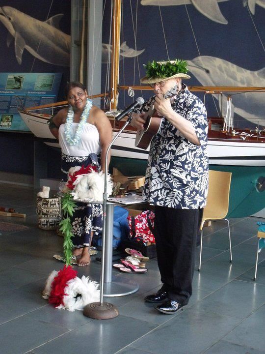 A man is playing a guitar while a woman stands behind him