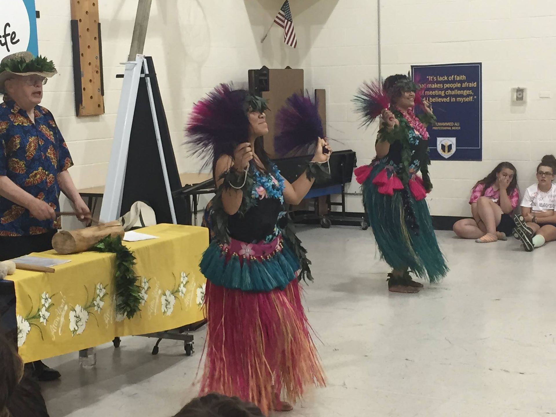 A group of women are performing a hula dance in a room.