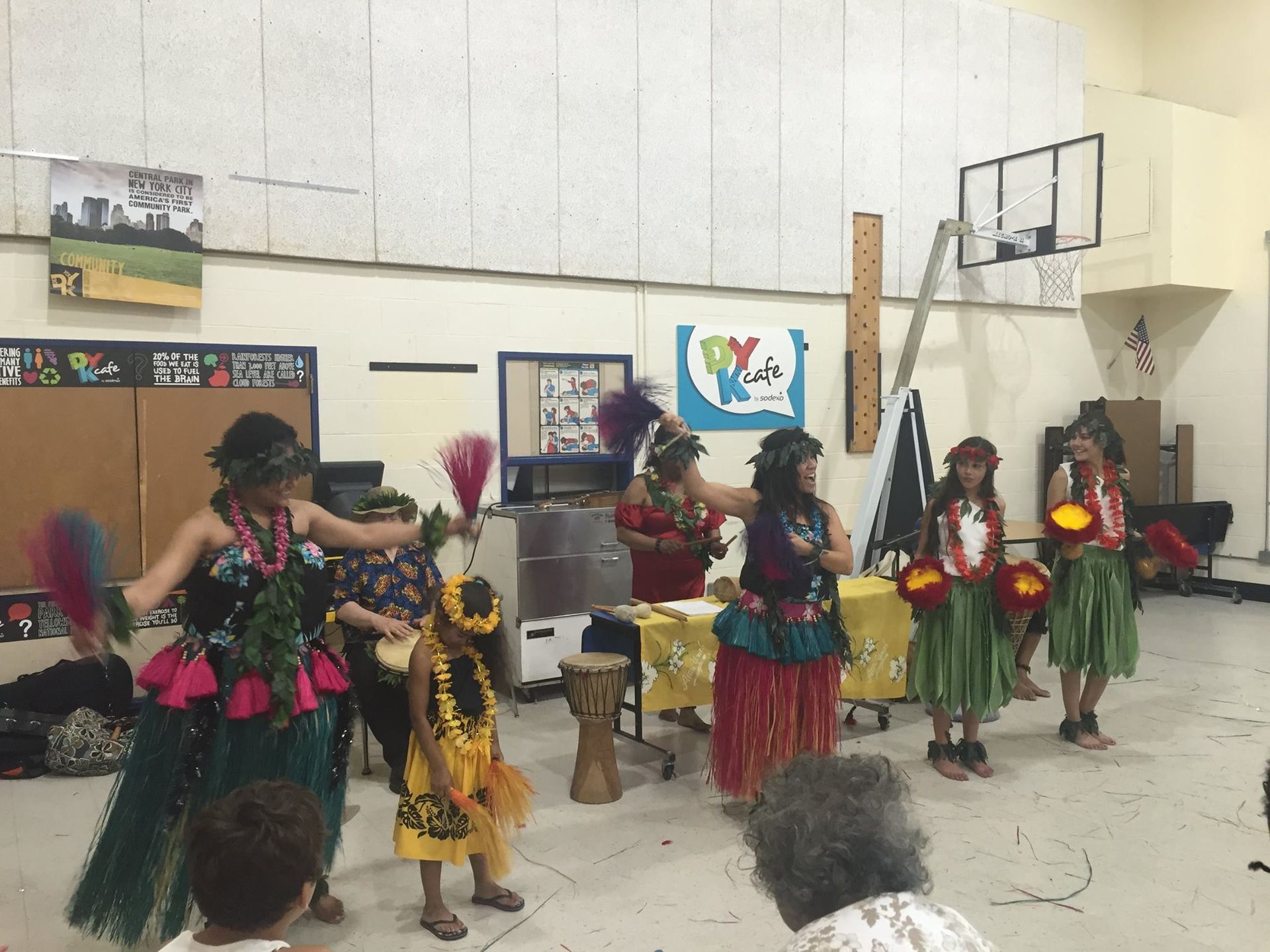 A group of people are performing a hula dance in a gym