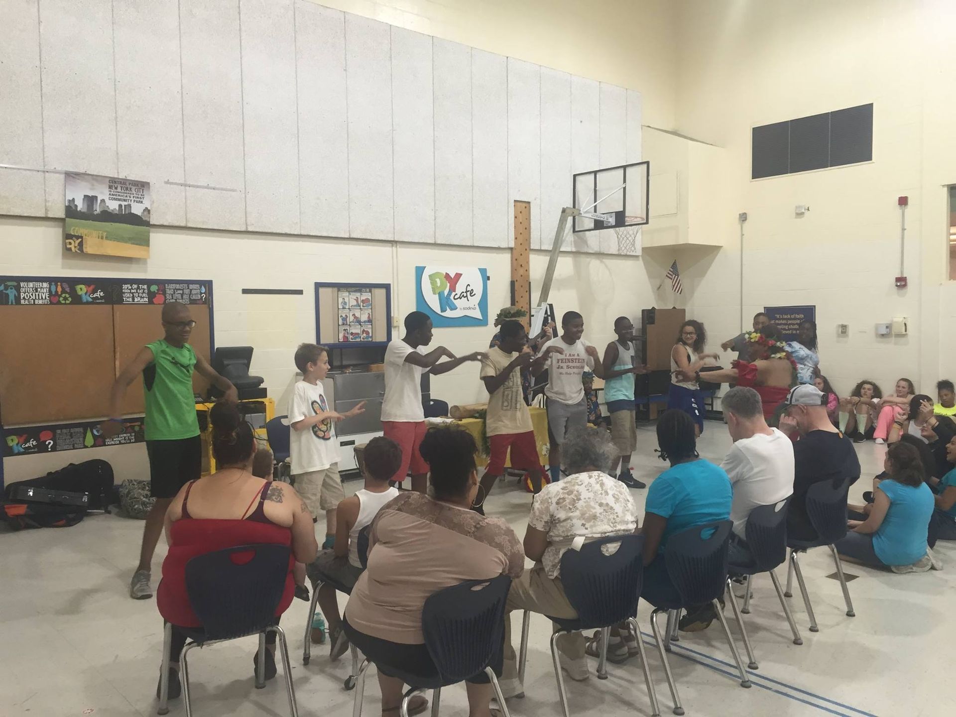 A group of people are sitting in chairs in a gym watching a performance.