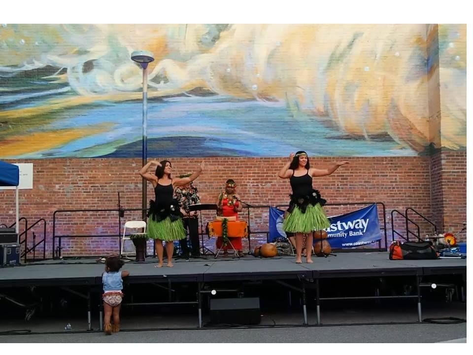 A group of women are dancing on a stage in front of a mural.