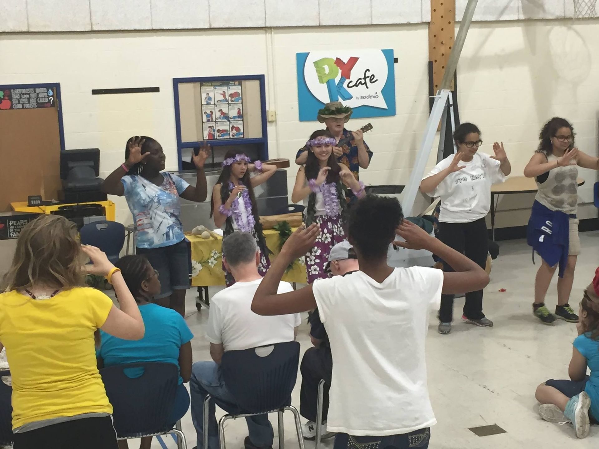 A group of people are dancing in front of a sign that says py cafe