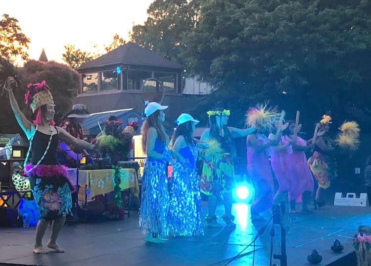 A group of women are dancing on a stage in front of a crowd.