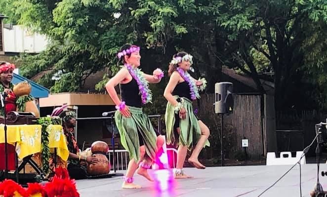 A group of women are dancing hula on a stage.
