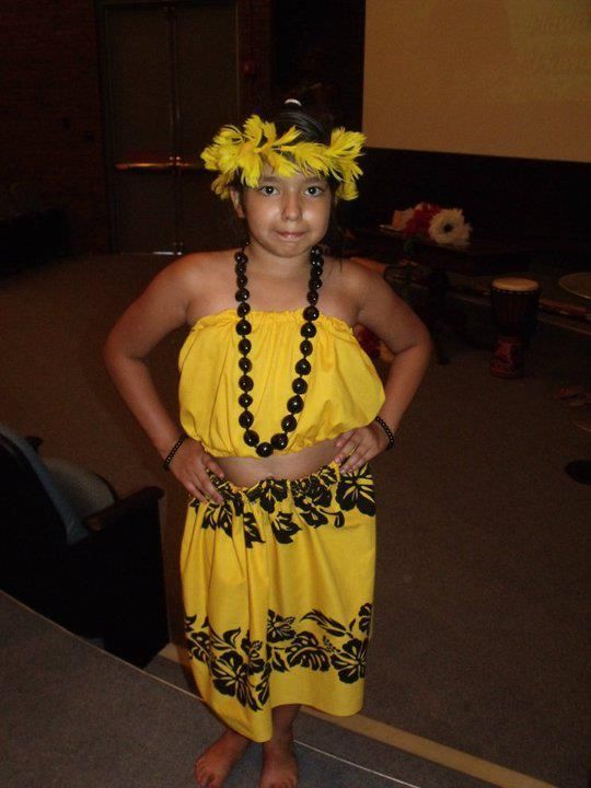 A young girl wearing a yellow top and black skirt