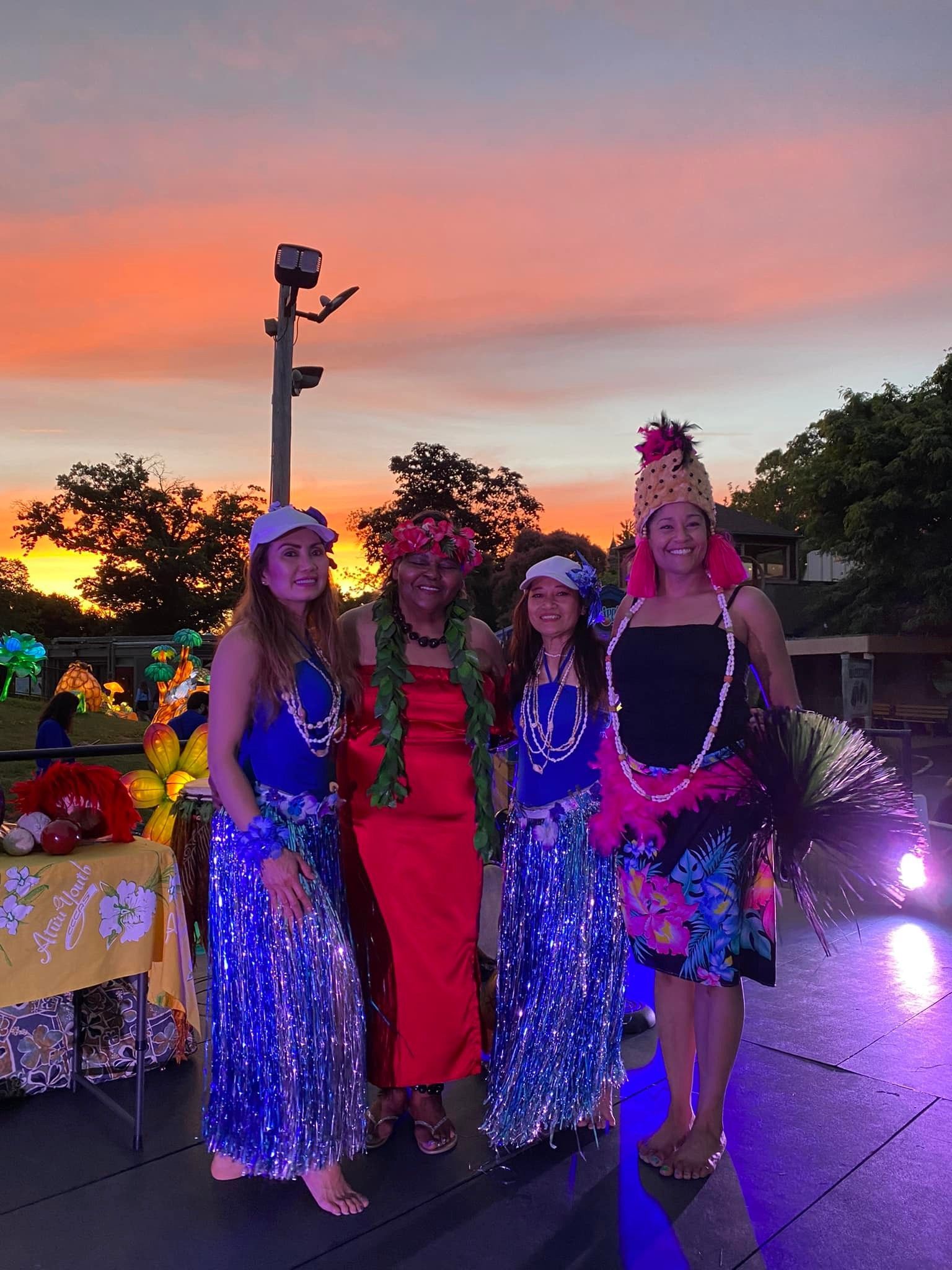 A group of women are posing for a picture in front of a sunset.