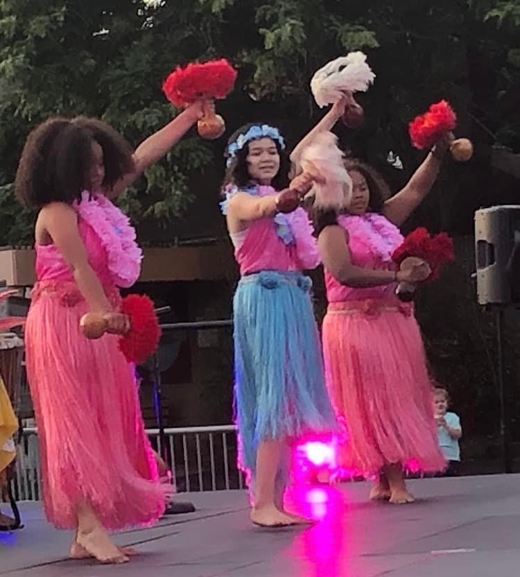 A group of women in pink and blue skirts are dancing on a stage