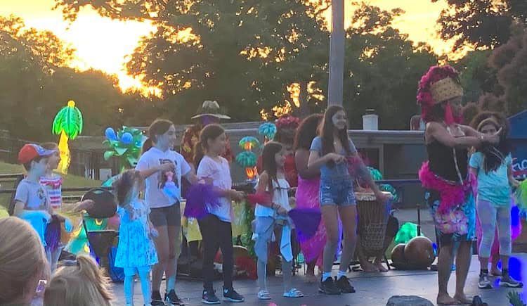 A group of children are dancing on a stage in front of a crowd.