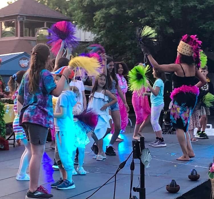 A group of people are dancing on a stage while wearing colorful costumes.
