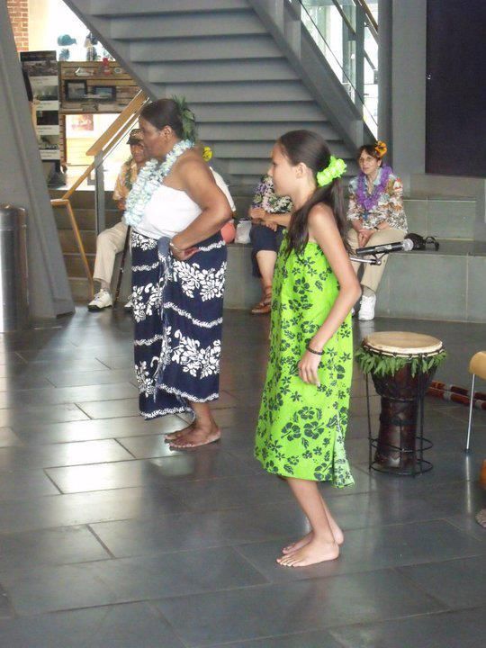A girl in a green dress is dancing in front of a drum