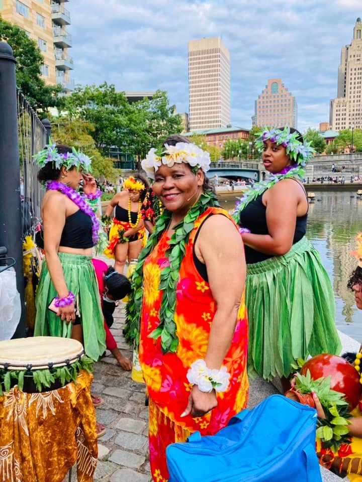 A group of women dressed in hawaiian costumes are standing on a sidewalk.