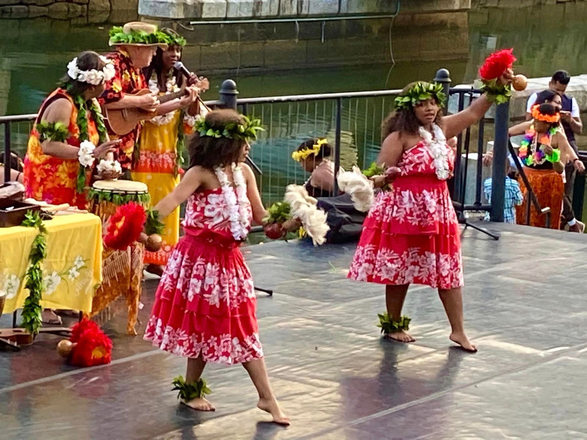 A group of women in hawaiian costumes are dancing on a stage