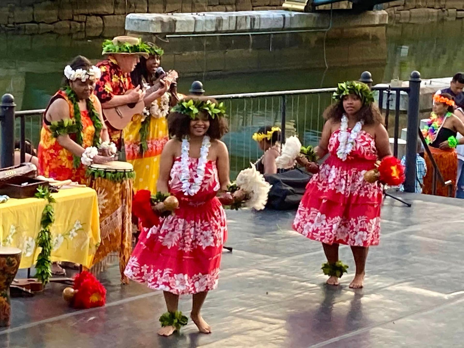 A group of women in hawaiian costumes are dancing on a stage