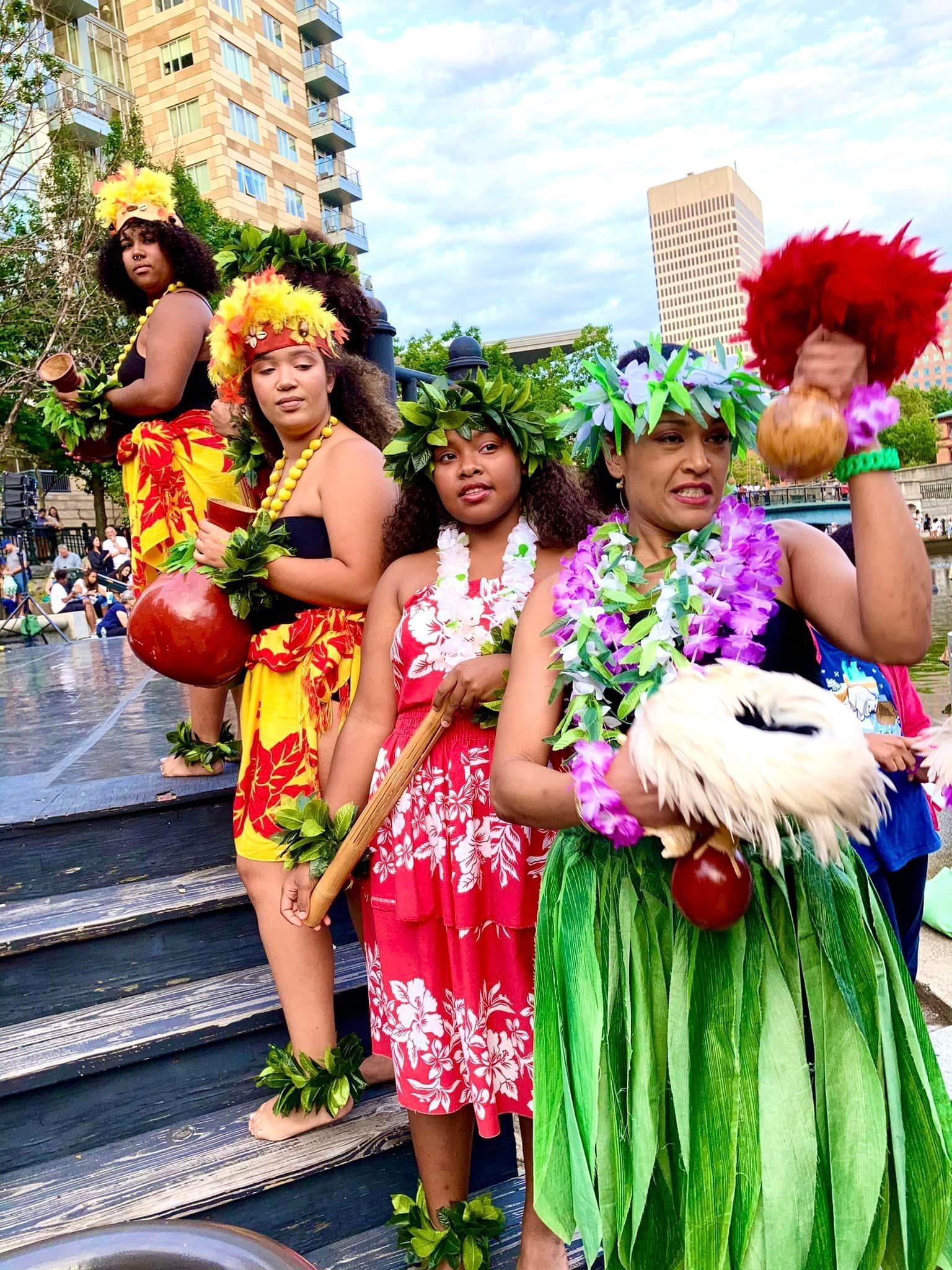A group of women dressed in hawaiian costumes are standing on a set of stairs.