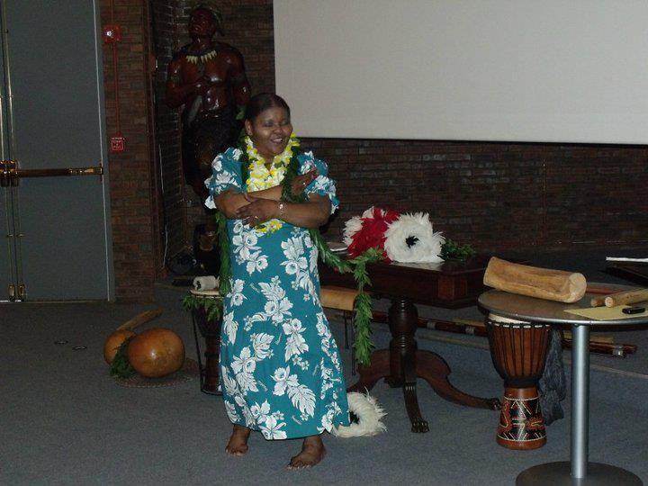 A woman in a hawaiian dress is standing in front of a table