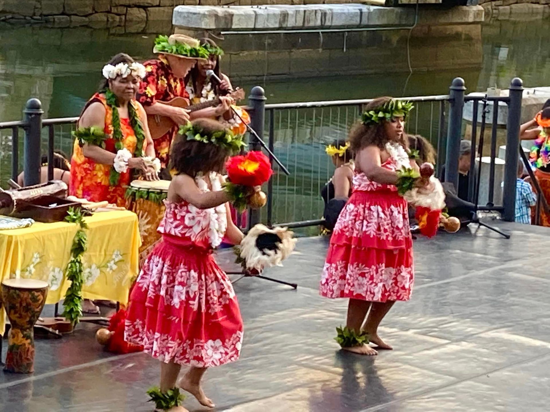 A group of people are dancing in front of a body of water.
