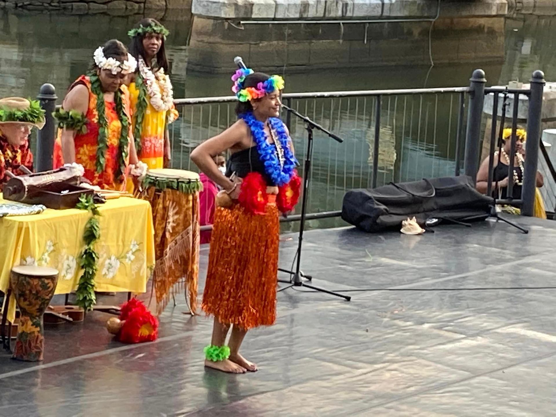 A woman wearing a lei is standing in front of a microphone on a stage.