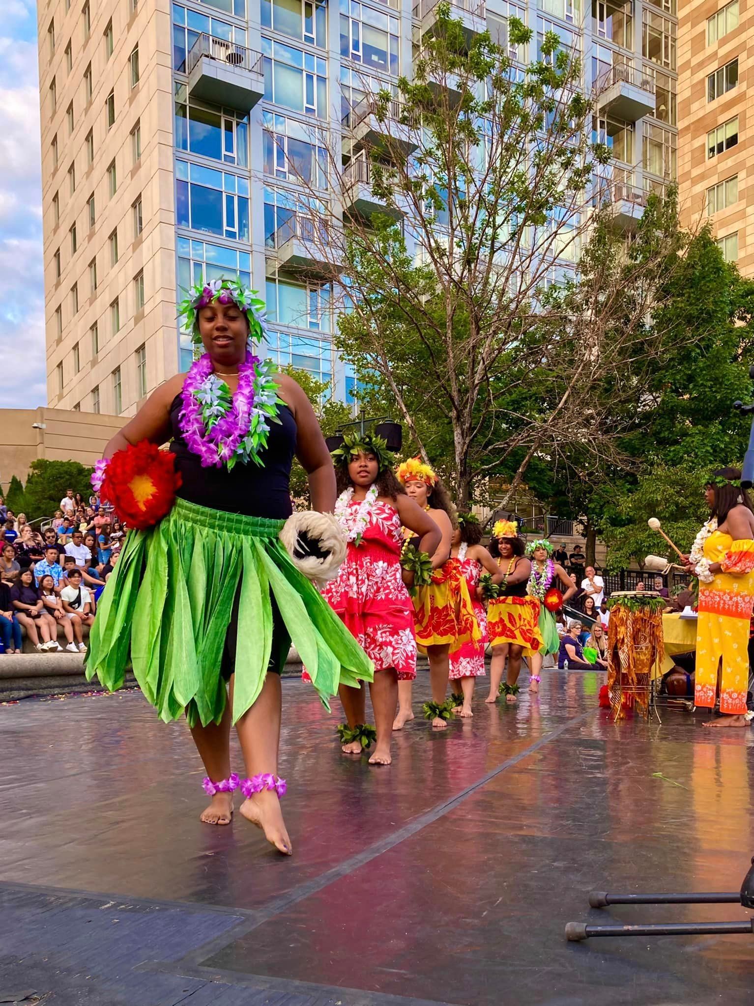 A group of people are dancing in a parade in front of a building.