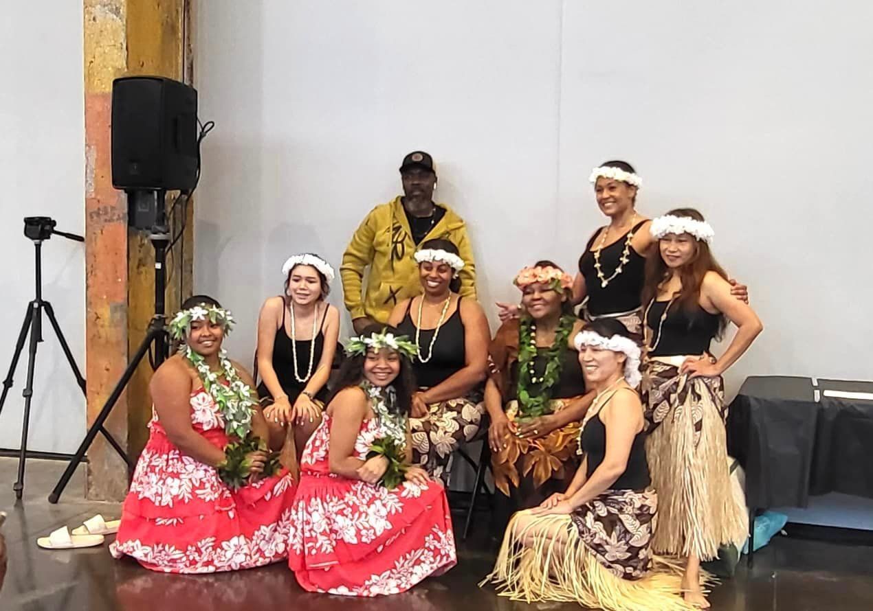 A group of people in hawaiian costumes are posing for a picture.