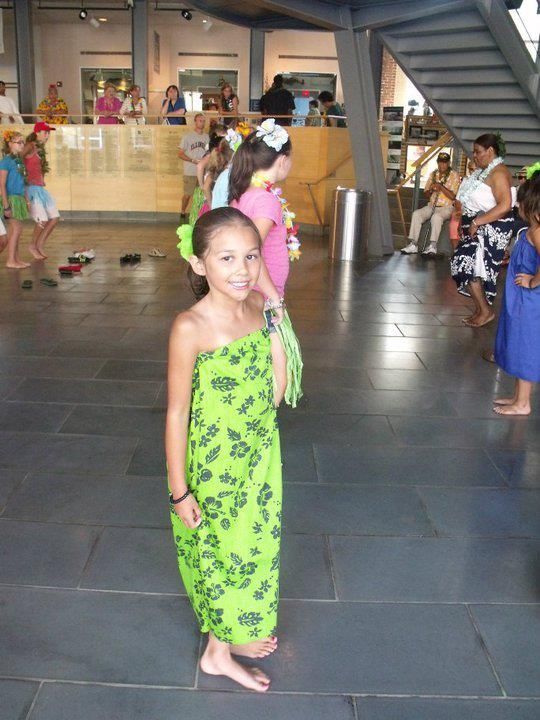 A girl in a green dress is standing on a tiled floor