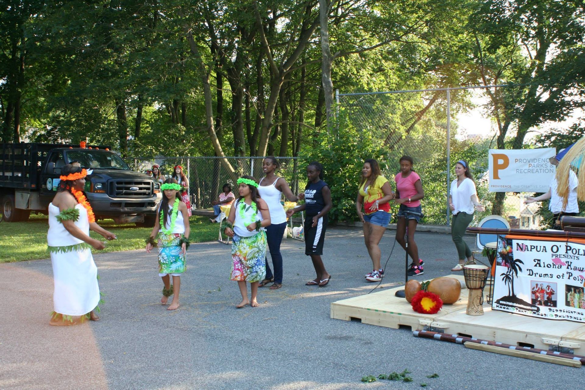 A group of people are dancing in front of a sign that says p.