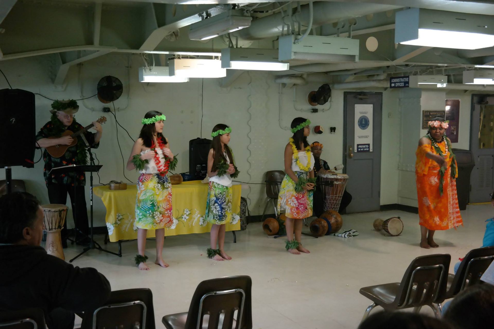 A group of women are dancing in a room with a man playing a guitar.