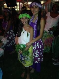 Two girls in hawaiian costumes are posing for a picture