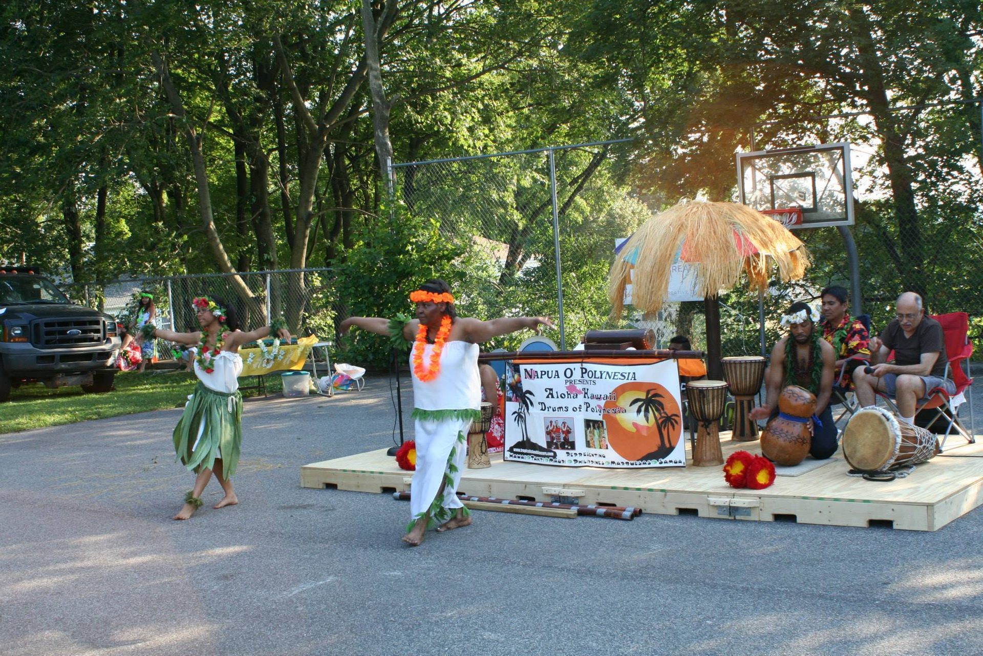 A group of people are dancing in front of a sign that says hawaii