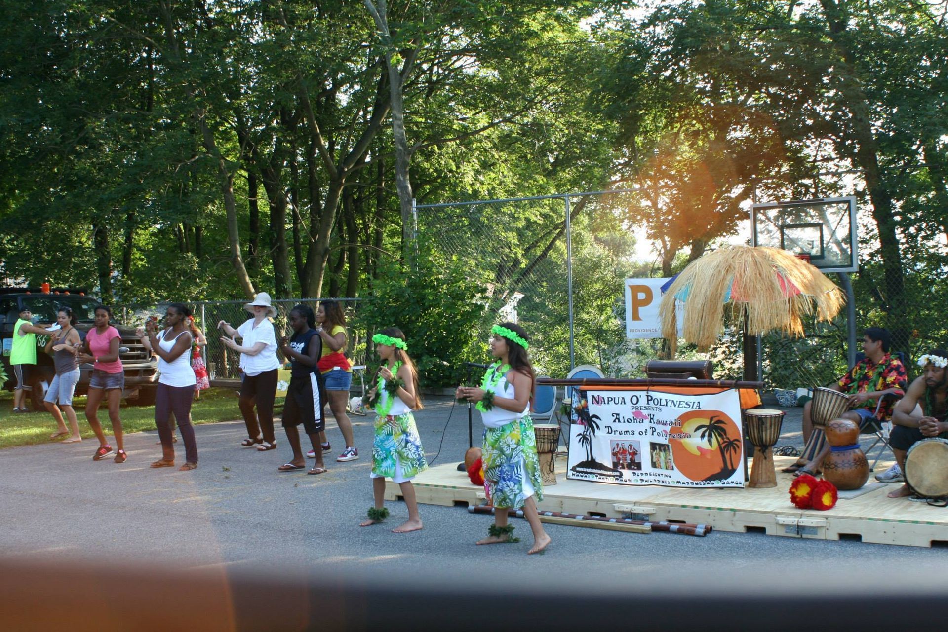 A group of people are dancing in front of a sign that says p.