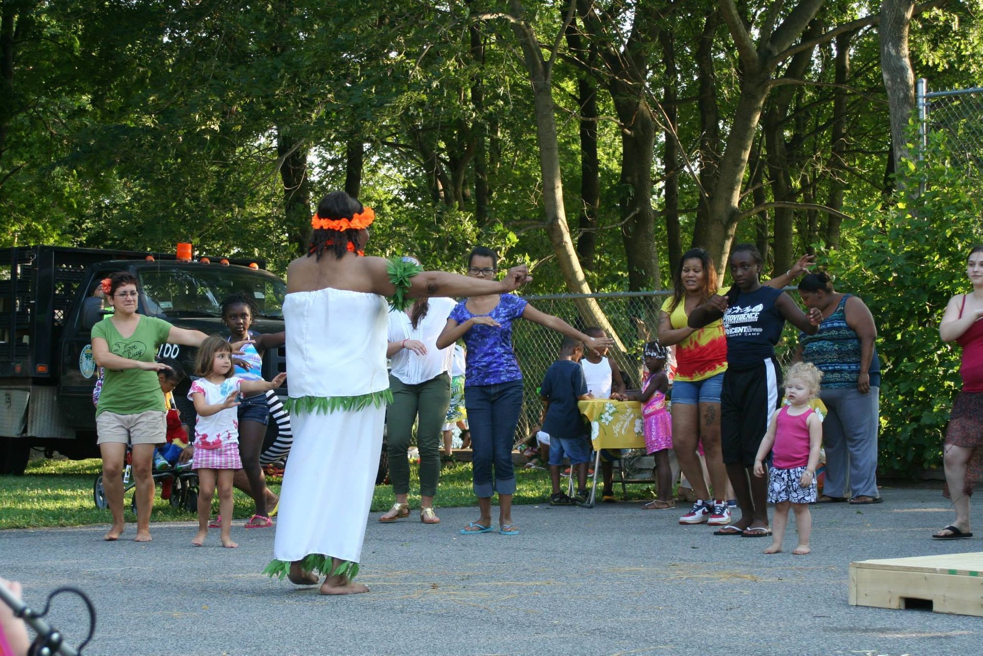A woman in a white dress is dancing in front of a crowd