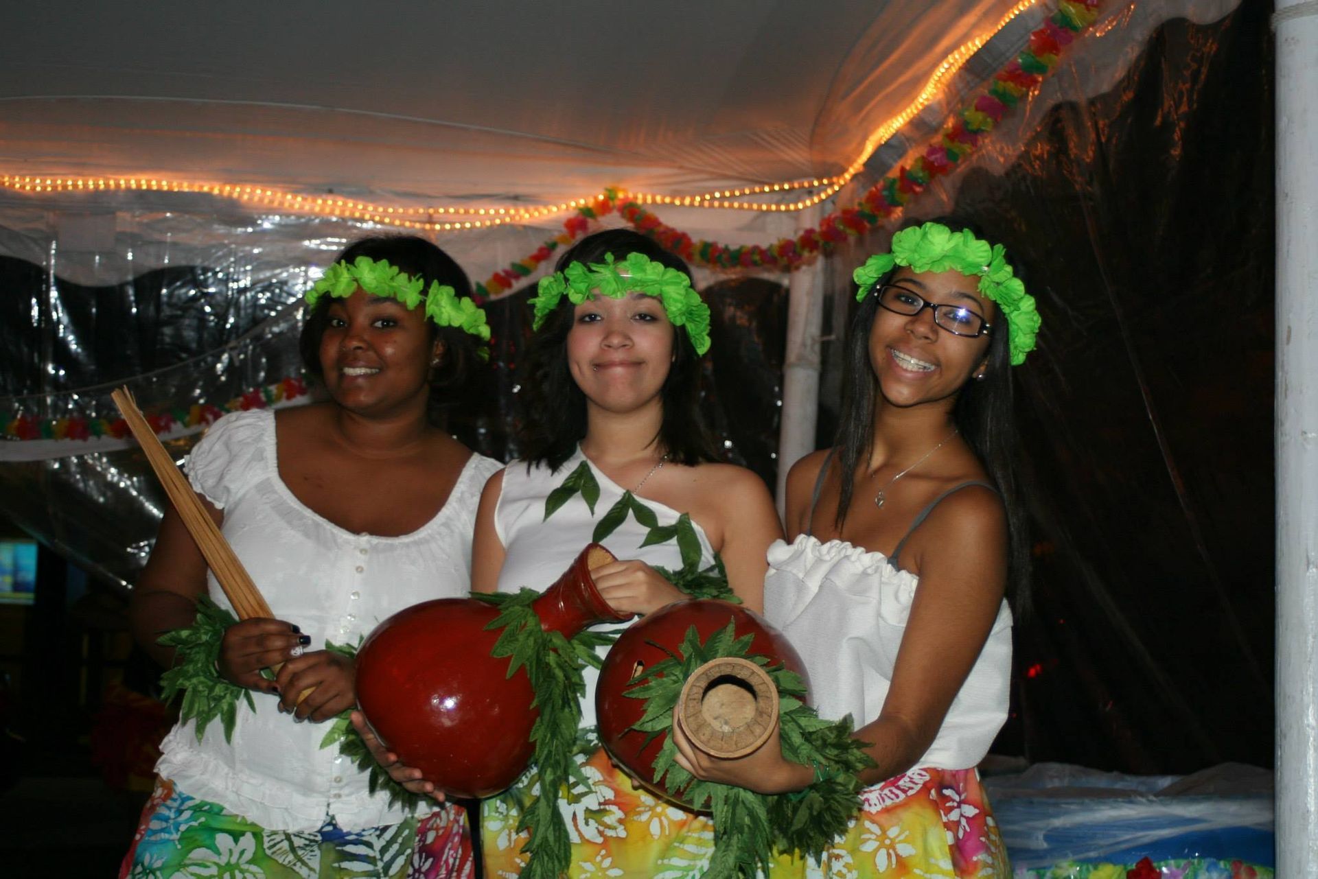 Three women in hawaiian costumes are posing for a picture