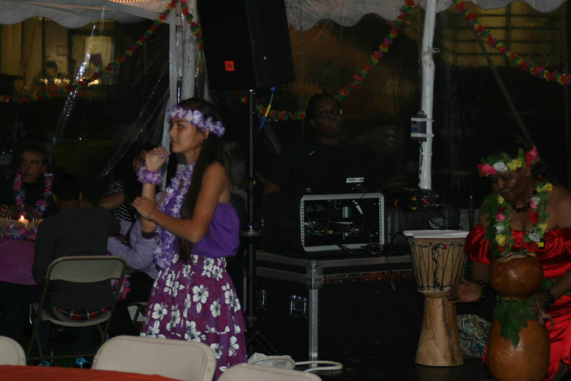 A girl is singing into a microphone while a man plays a drum.