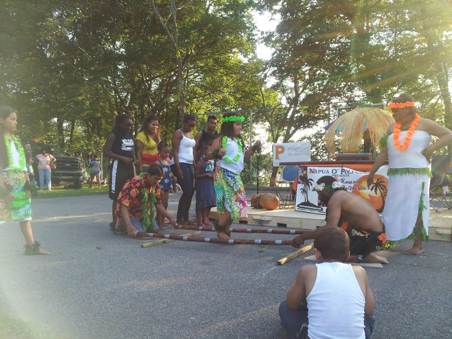 A man in a white tank top watches a group of people perform