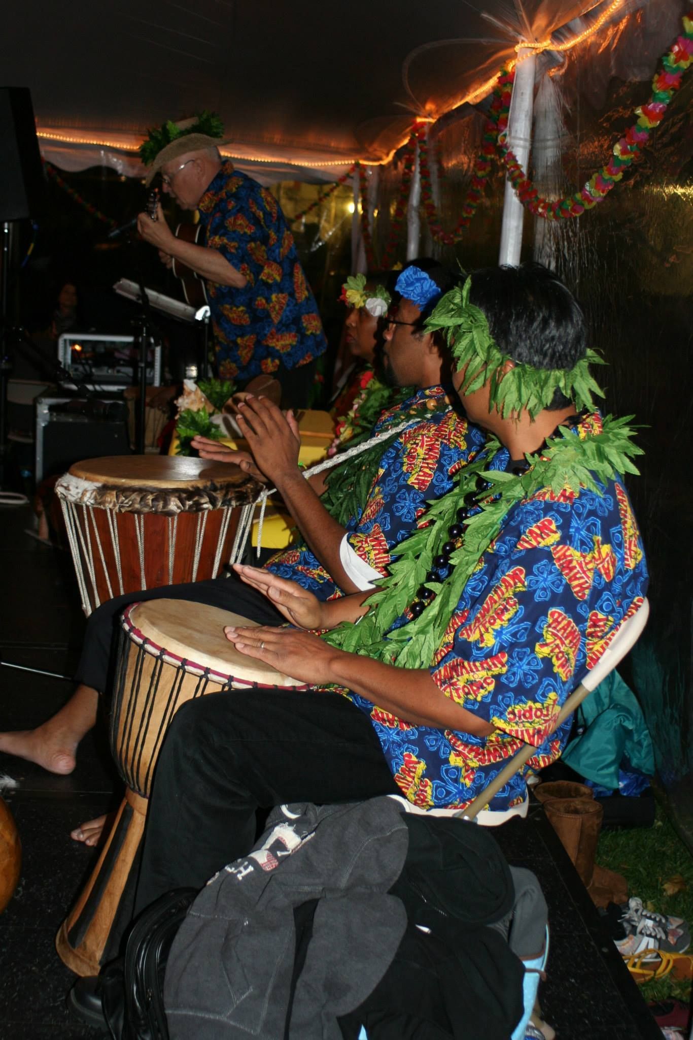 A group of people are playing drums in a dark room.