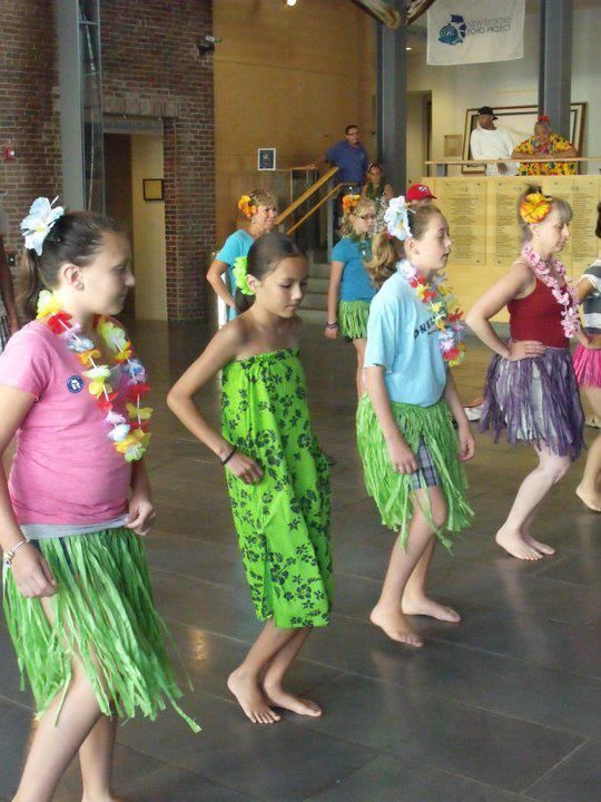 A group of young girls wearing hawaiian skirts are dancing