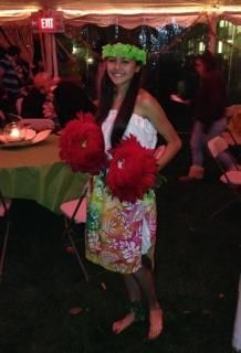 A woman in a hawaiian costume is holding red pom poms