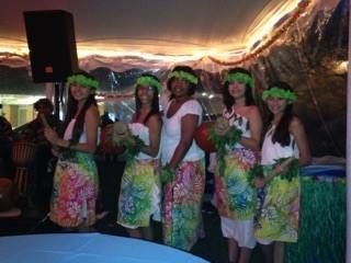 A group of women in hawaiian outfits are standing next to each other