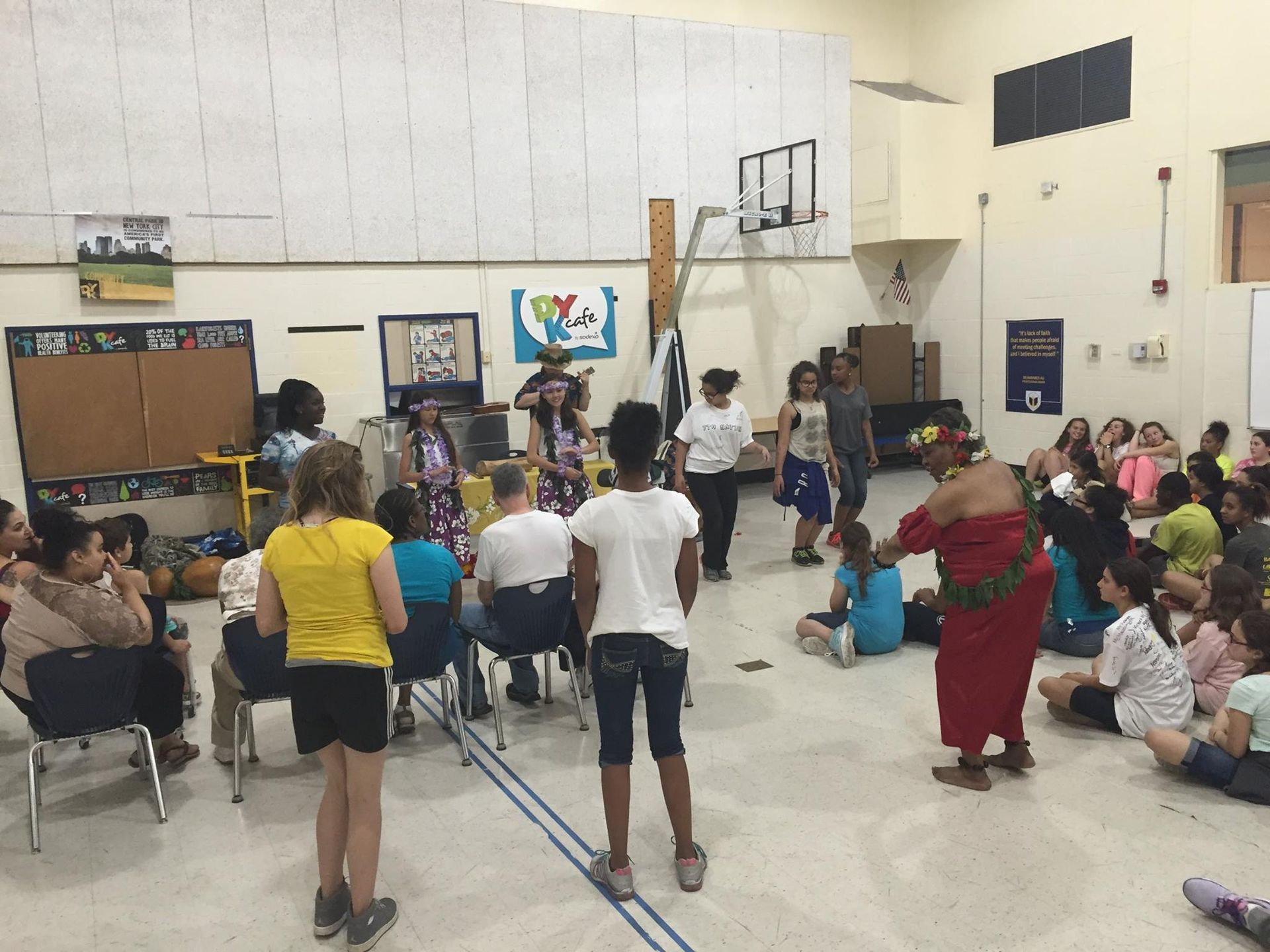 A group of people are standing in a gym with a basketball hoop in the background