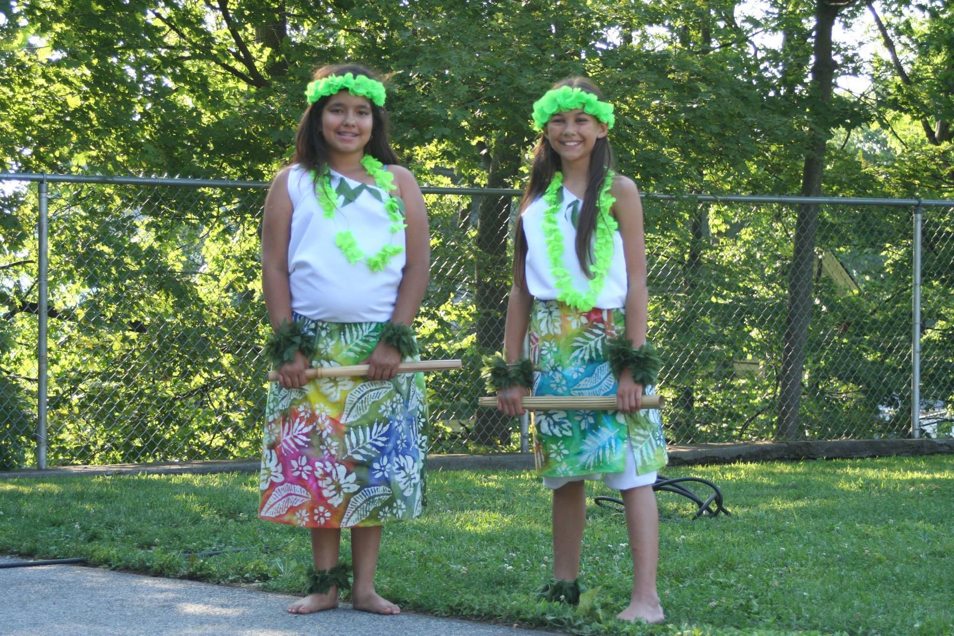 Two girls in hawaiian outfits are standing next to each other