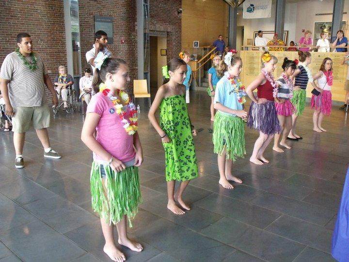 A group of young girls are standing in a line wearing hawaiian skirts