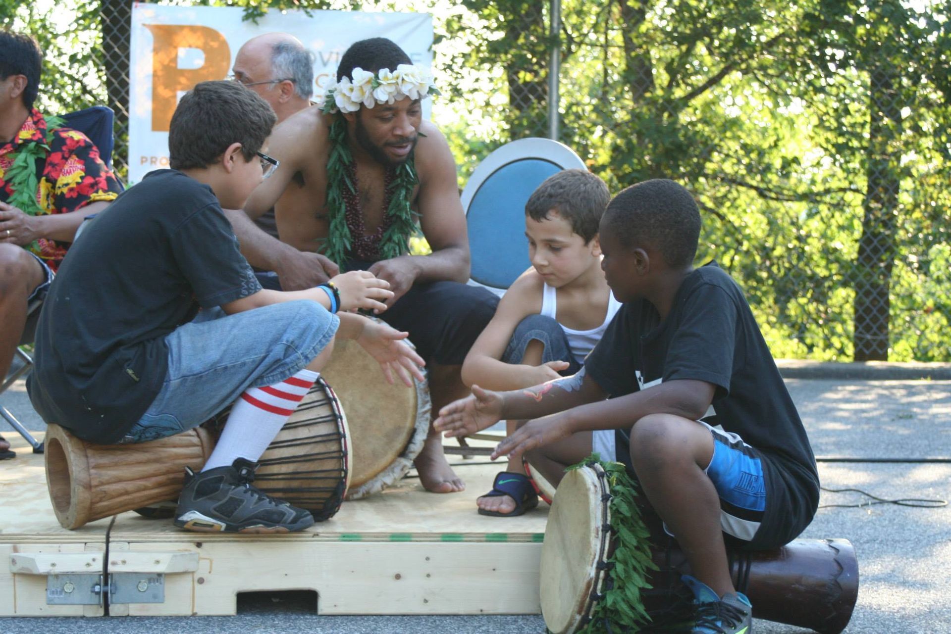 A group of young boys are playing drums in front of a sign that has the letter p on it