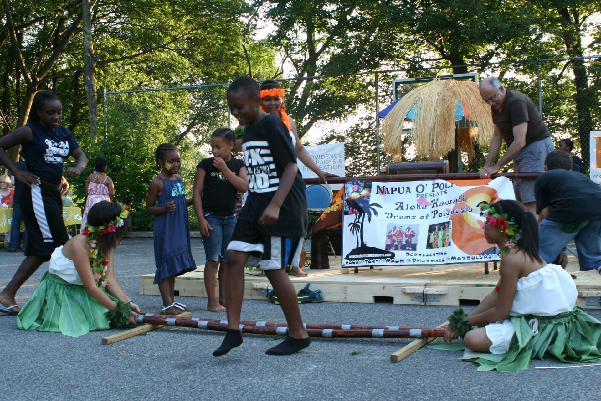 A group of people are dancing in front of a sign that says hawaii