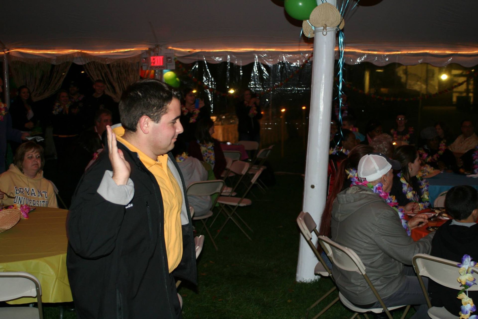 A man is holding a banana in front of a crowd at a party