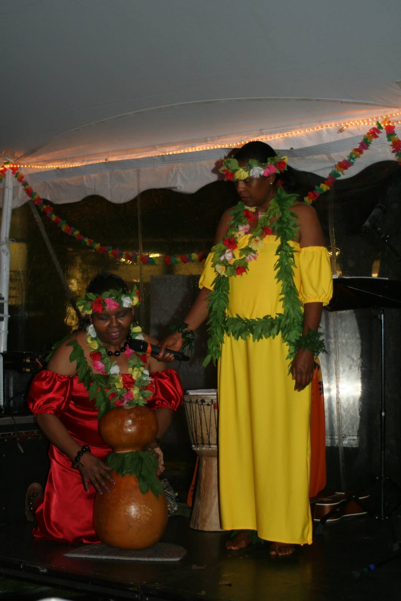 Two women in hawaiian costumes are standing next to each other on a stage.
