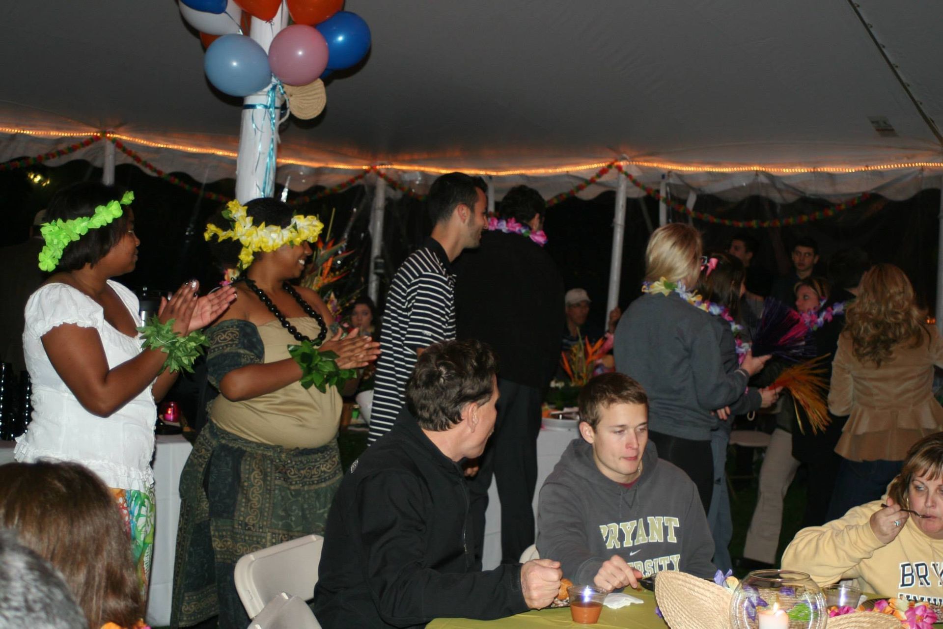 A group of people are gathered under a tent and one of them is wearing a sweatshirt that says ' tcu '