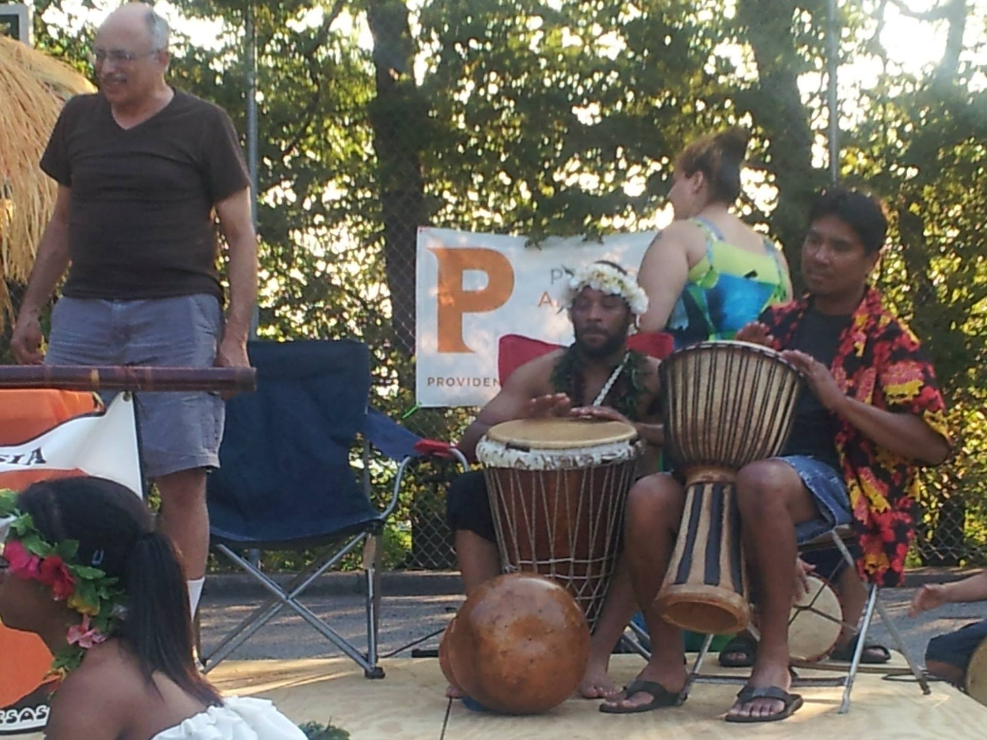 A group of people playing drums in front of a sign that says p.