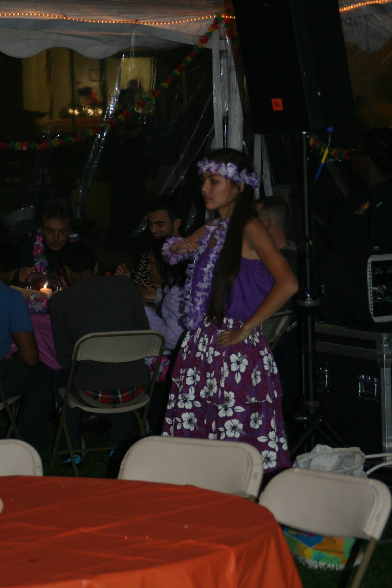 A woman in a purple dress is standing in front of a crowd of people.