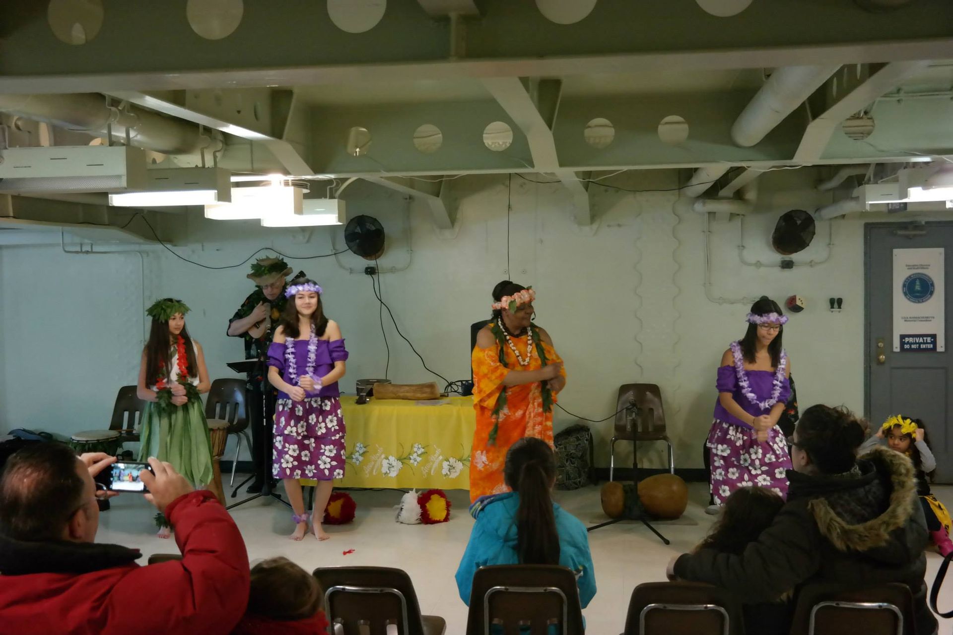 A man is taking a picture of a group of people dancing in front of a sign that says police