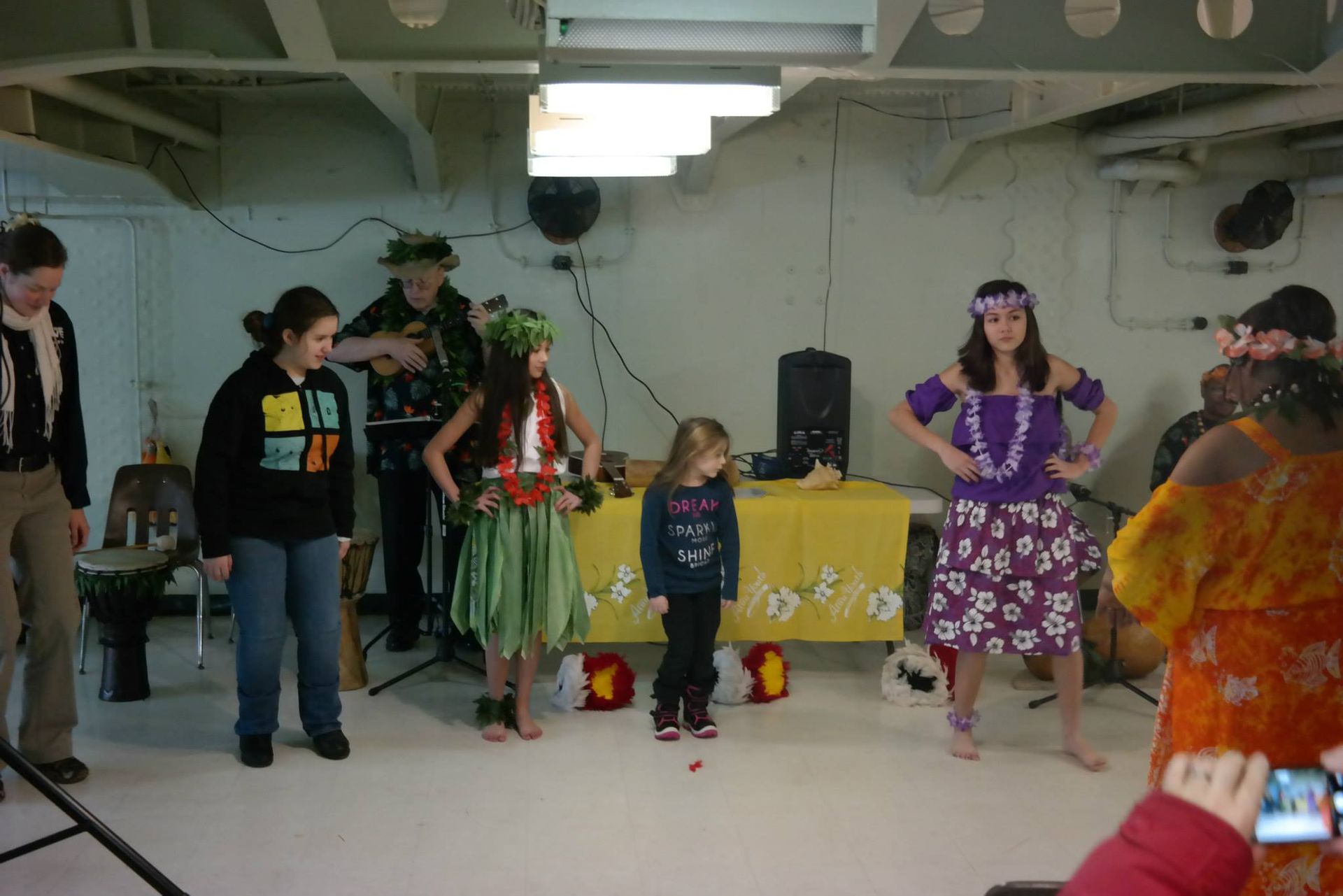 A group of people in hawaiian costumes are dancing in a room